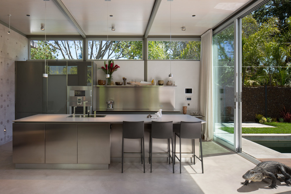 Inspiration for a mid-sized modern single-wall concrete floor open concept kitchen remodel in San Francisco with a double-bowl sink, flat-panel cabinets, stainless steel cabinets, concrete countertops, white backsplash, stainless steel appliances and an island