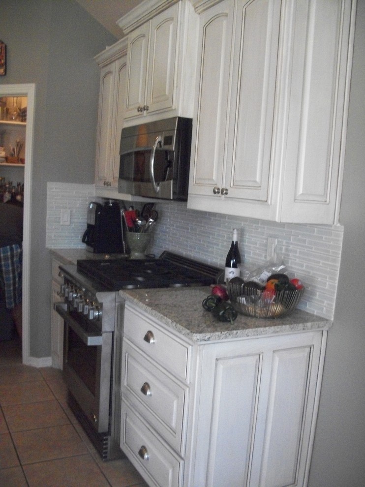 Bild på ett mellanstort funkis kök, med en undermonterad diskho, luckor med upphöjd panel, skåp i slitet trä, granitbänkskiva, vitt stänkskydd, stänkskydd i glaskakel, rostfria vitvaror och klinkergolv i porslin