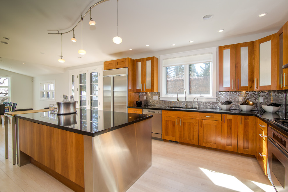 Inspiration for a large transitional l-shaped light wood floor and beige floor eat-in kitchen remodel in Denver with an undermount sink, shaker cabinets, medium tone wood cabinets, quartz countertops, metallic backsplash, mosaic tile backsplash, stainless steel appliances, an island and black countertops
