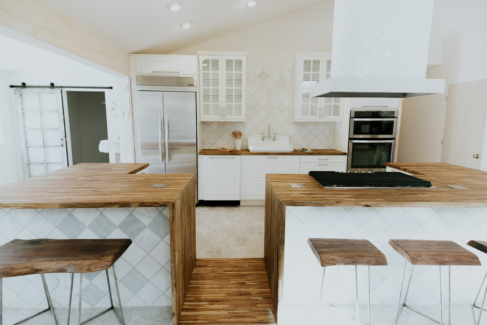 Idéer för att renovera ett mellanstort nordiskt brun brunt kök, med en rustik diskho, luckor med glaspanel, vita skåp, träbänkskiva, vitt stänkskydd, stänkskydd i keramik, rostfria vitvaror, klinkergolv i porslin, flera köksöar och grått golv
