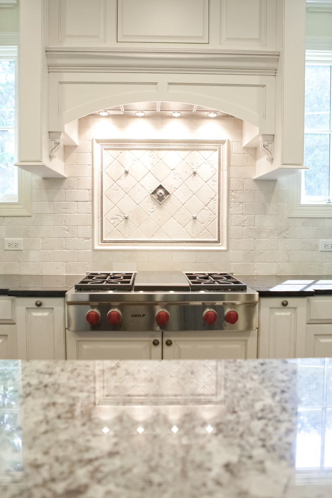 Esempio di una cucina chic di medie dimensioni con ante con bugna sagomata, ante bianche, top in granito, paraspruzzi bianco, paraspruzzi in mattoni e elettrodomestici in acciaio inossidabile