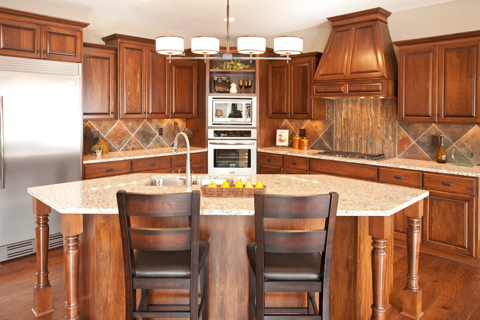ミネアポリスにあるトラディショナルスタイルのおしゃれなキッチン (レイズドパネル扉のキャビネット、シルバーの調理設備、マルチカラーのキッチンパネル、中間色木目調キャビネット、スレートのキッチンパネル) の写真