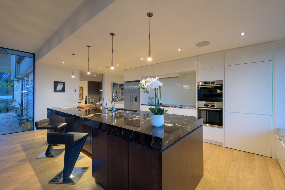 Offene, Zweizeilige Moderne Küche mit offenen Schränken, hellem Holzboden, Kücheninsel und braunem Boden in Sonstige