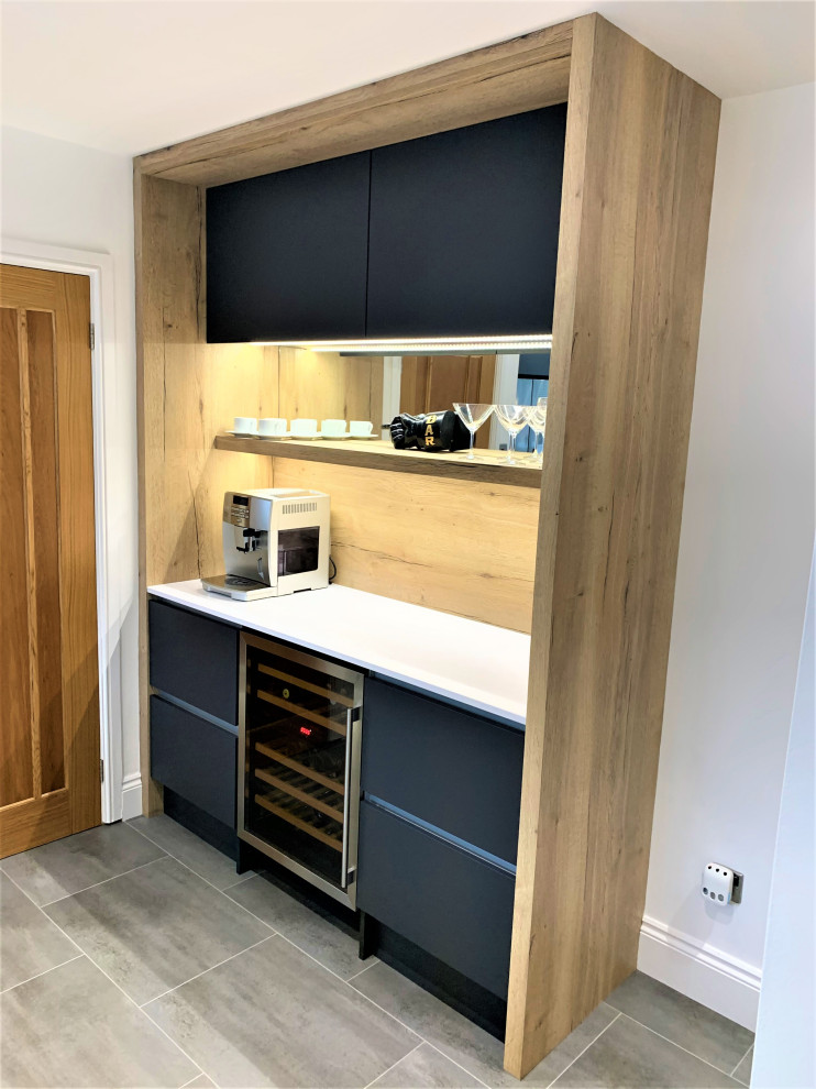 Medium sized contemporary u-shaped open plan kitchen in Other with a single-bowl sink, flat-panel cabinets, medium wood cabinets, composite countertops, black appliances, vinyl flooring, an island and white worktops.