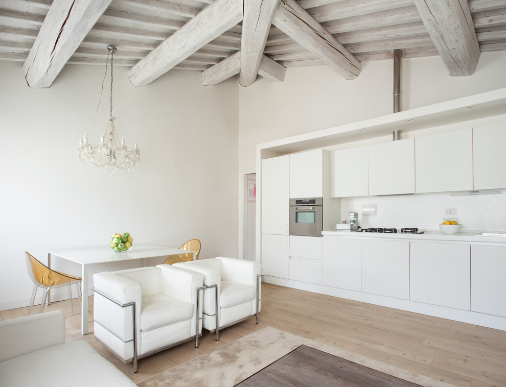 Ejemplo de cocina lineal minimalista grande abierta con suelo de madera clara, armarios con paneles lisos, puertas de armario blancas, salpicadero blanco y electrodomésticos de acero inoxidable
