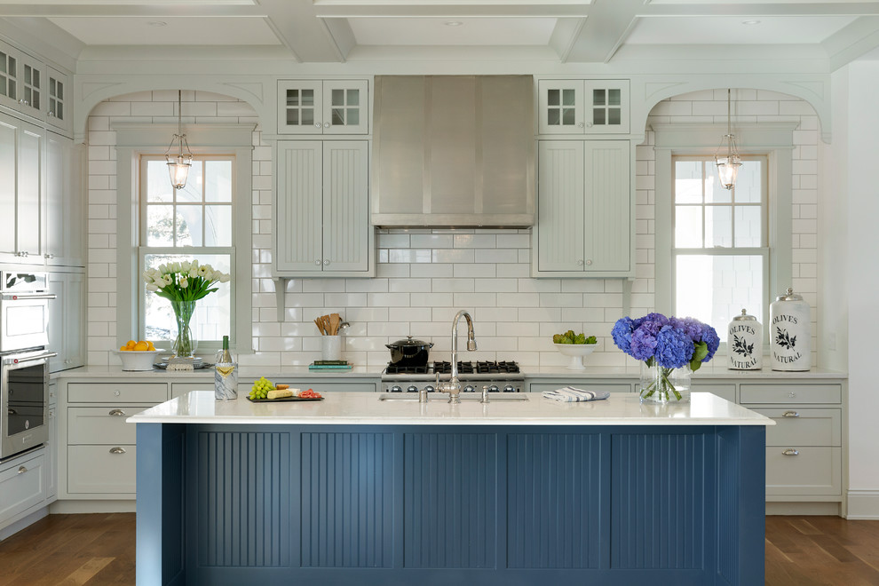Inredning av ett klassiskt kök, med en undermonterad diskho, luckor med infälld panel, bänkskiva i koppar, vitt stänkskydd, rostfria vitvaror, en köksö, blå skåp, stänkskydd i tunnelbanekakel och ljust trägolv
