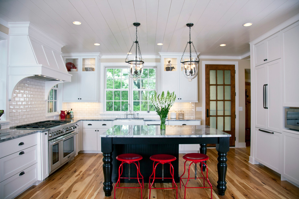 Klassische Küche in L-Form mit weißen Schränken, Küchenrückwand in Weiß, Rückwand aus Metrofliesen und Elektrogeräten mit Frontblende in Minneapolis