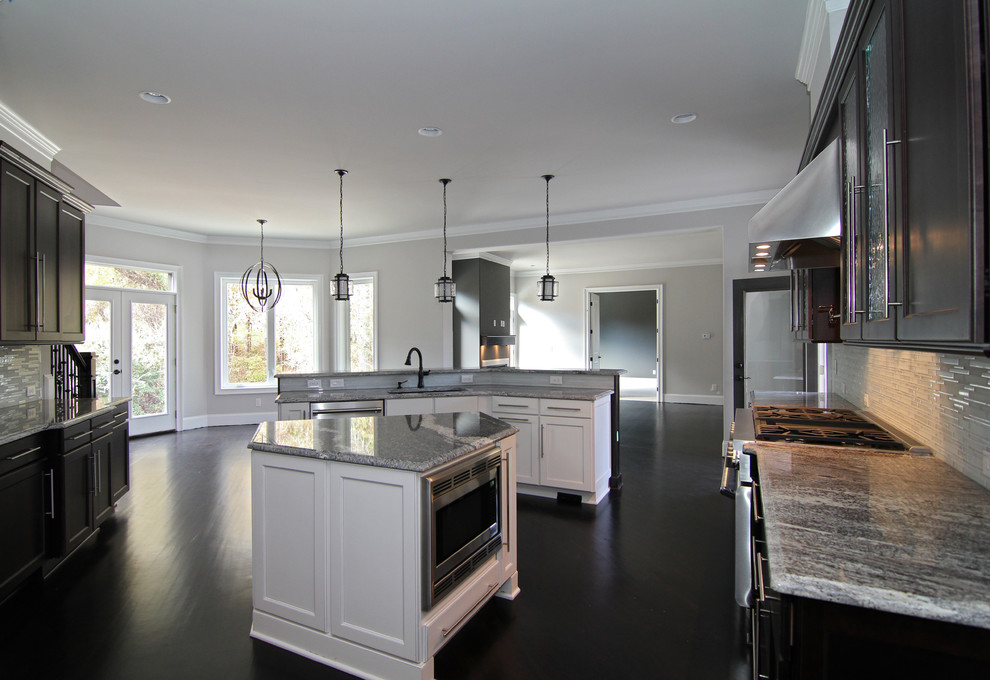 Eat-in kitchen - huge traditional u-shaped dark wood floor eat-in kitchen idea in Raleigh with a single-bowl sink, recessed-panel cabinets, white cabinets, granite countertops, white backsplash, stainless steel appliances and two islands