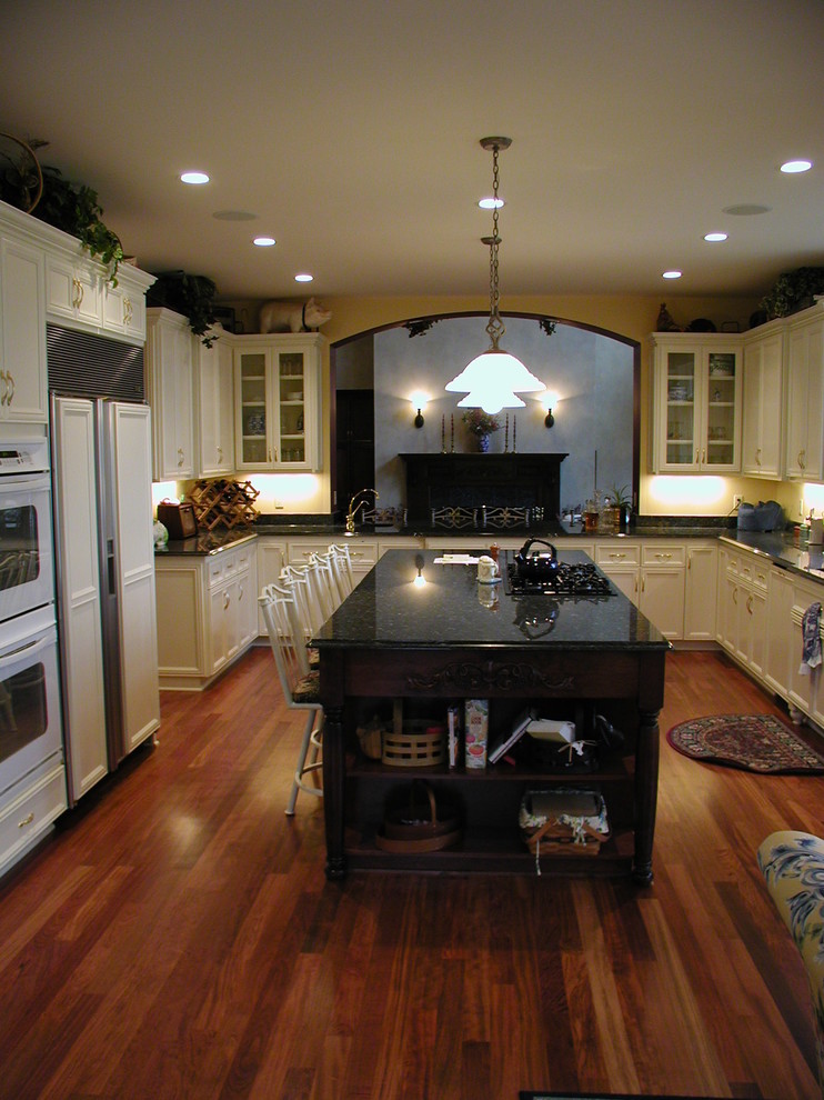 Klassisk inredning av ett avskilt, mellanstort u-kök, med en undermonterad diskho, skåp i shakerstil, vita skåp, bänkskiva i koppar, beige stänkskydd, stänkskydd i keramik, vita vitvaror, mellanmörkt trägolv, en köksö och brunt golv