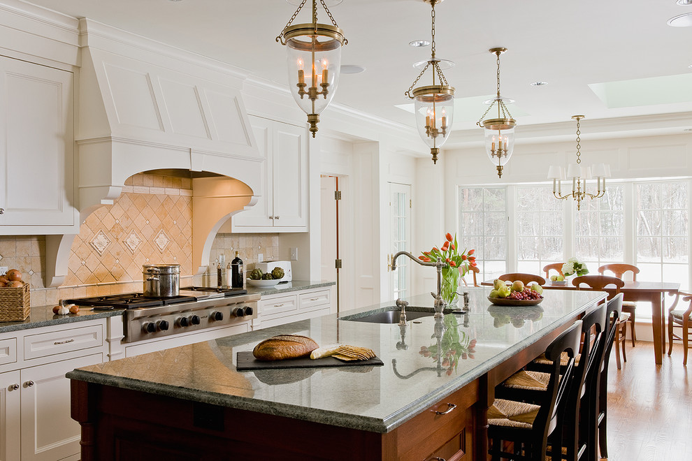 Zweizeilige Klassische Wohnküche mit Unterbauwaschbecken, Schrankfronten mit vertiefter Füllung, weißen Schränken, Küchenrückwand in Beige, Küchengeräten aus Edelstahl, braunem Holzboden und Kücheninsel in Boston