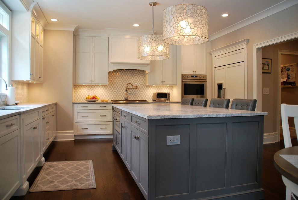 Exempel på ett mellanstort klassiskt kök, med en undermonterad diskho, luckor med infälld panel, vita skåp, marmorbänkskiva, vitt stänkskydd, stänkskydd i keramik, rostfria vitvaror, mörkt trägolv, en köksö och brunt golv