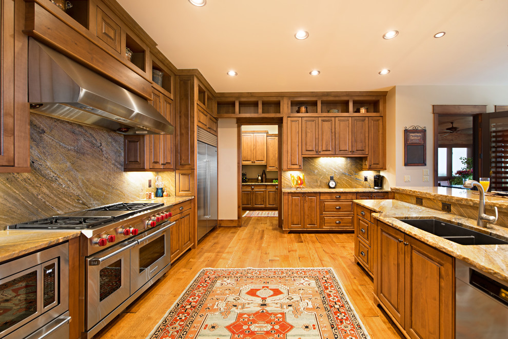This is an example of an expansive traditional l-shaped open plan kitchen in Denver with a submerged sink, recessed-panel cabinets, medium wood cabinets, granite worktops, multi-coloured splashback, stone slab splashback, stainless steel appliances, medium hardwood flooring and a breakfast bar.