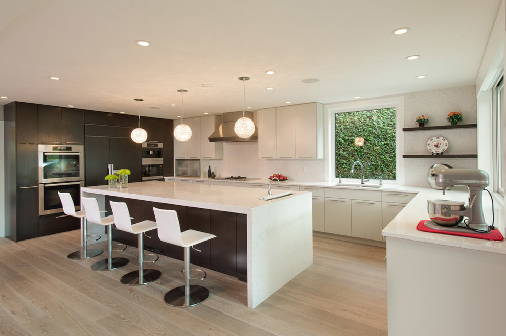 Photo of a contemporary u-shaped open plan kitchen in Vancouver with a submerged sink, flat-panel cabinets, dark wood cabinets, integrated appliances, engineered stone countertops, white splashback and stone slab splashback.