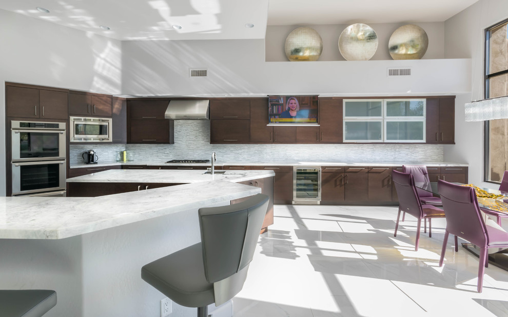 Photo of an expansive traditional u-shaped open plan kitchen in Phoenix with a submerged sink, flat-panel cabinets, dark wood cabinets, marble worktops, grey splashback, glass tiled splashback, stainless steel appliances, marble flooring and multiple islands.