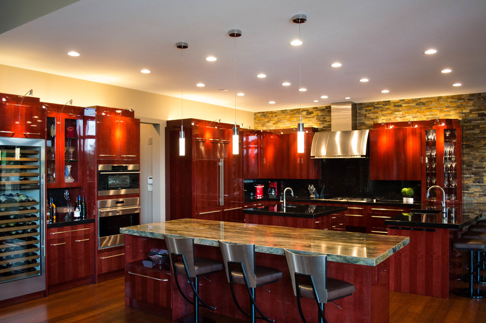 Foto på ett mycket stort funkis kök, med en undermonterad diskho, släta luckor, granitbänkskiva, svart stänkskydd, stänkskydd i sten, rostfria vitvaror, mellanmörkt trägolv och flera köksöar