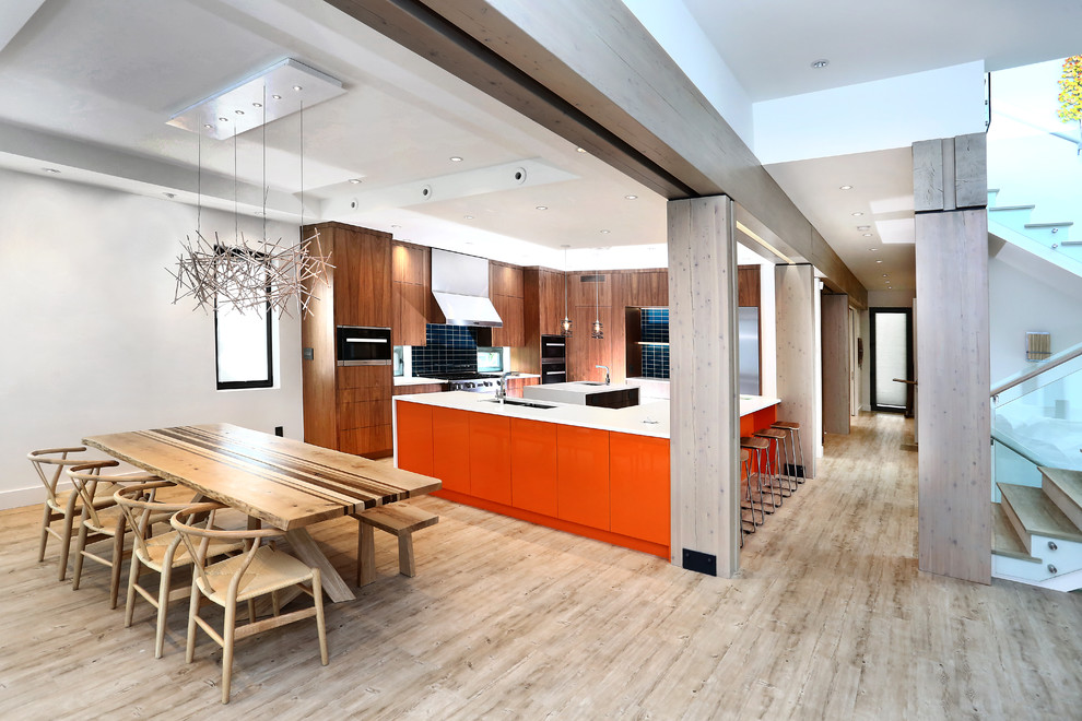 Inspiration for an expansive world-inspired l-shaped kitchen/diner in Vancouver with a built-in sink, flat-panel cabinets, light wood cabinets, engineered stone countertops, blue splashback, glass tiled splashback, stainless steel appliances, bamboo flooring, multiple islands and grey floors.