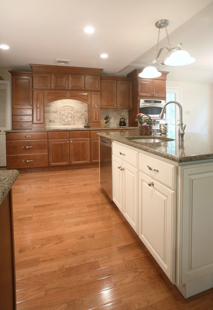 Exempel på ett mycket stort klassiskt kök och matrum, med en undermonterad diskho, luckor med upphöjd panel, skåp i mellenmörkt trä, granitbänkskiva, beige stänkskydd, stänkskydd i keramik, rostfria vitvaror, mellanmörkt trägolv och en köksö