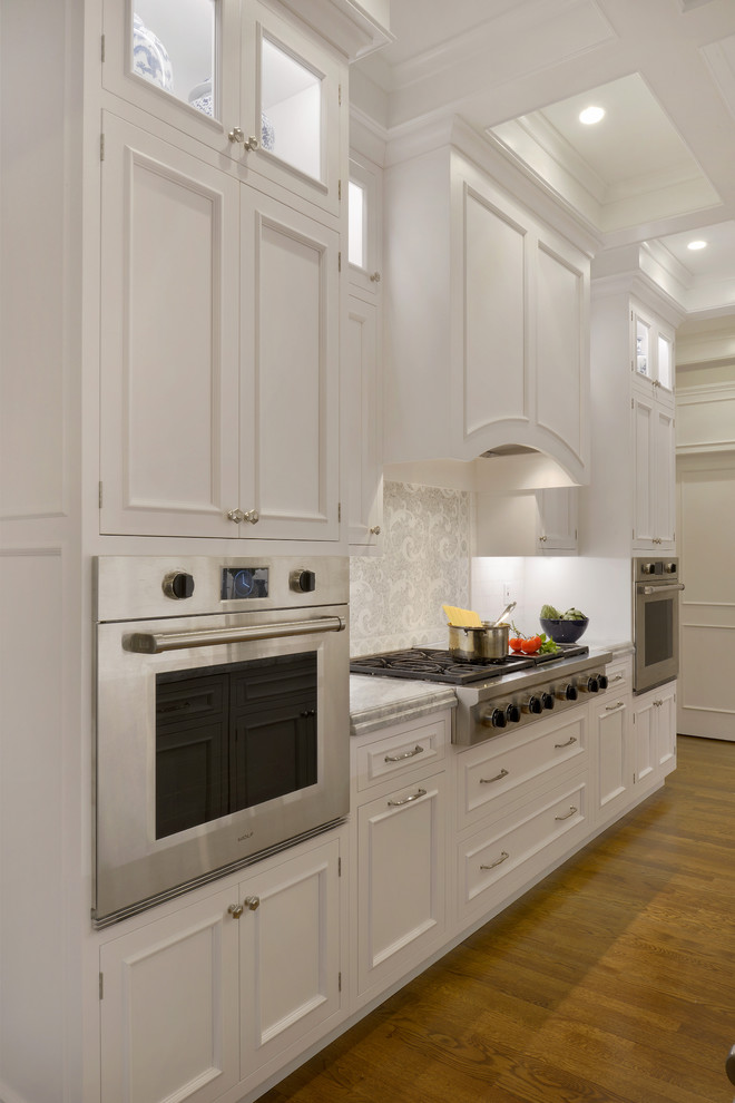 Inspiration for a huge timeless u-shaped medium tone wood floor eat-in kitchen remodel in New York with an undermount sink, flat-panel cabinets, white cabinets, quartzite countertops, white backsplash, stainless steel appliances and an island