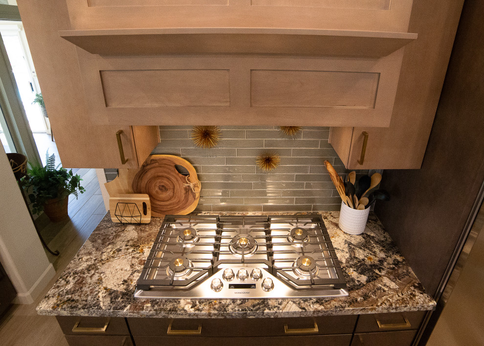 フェニックスにある高級な広いシャビーシック調のおしゃれなキッチン (アンダーカウンターシンク、フラットパネル扉のキャビネット、中間色木目調キャビネット、御影石カウンター、グレーのキッチンパネル、ガラスタイルのキッチンパネル、シルバーの調理設備、茶色い床、マルチカラーのキッチンカウンター) の写真