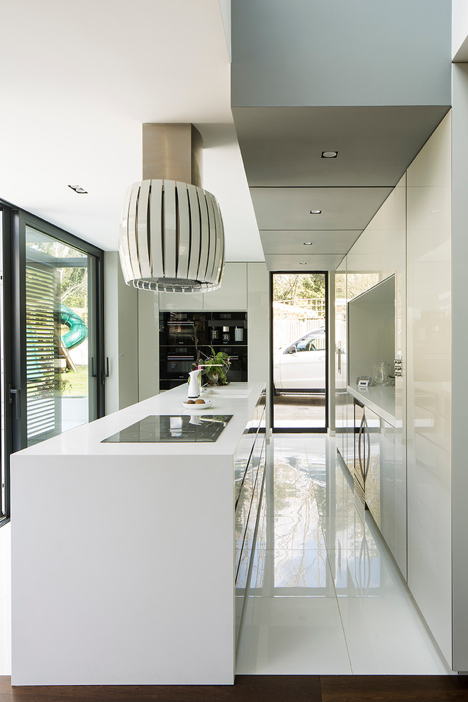 Inspiration for a medium sized contemporary u-shaped enclosed kitchen in London with a double-bowl sink, flat-panel cabinets, white cabinets, black appliances, an island, composite countertops and porcelain flooring.