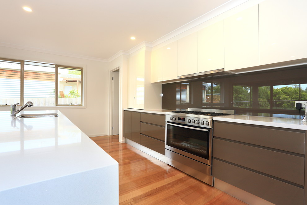 Example of a mid-sized minimalist galley medium tone wood floor eat-in kitchen design in Melbourne with an undermount sink, flat-panel cabinets, brown cabinets, quartz countertops, brown backsplash, glass sheet backsplash, stainless steel appliances and an island
