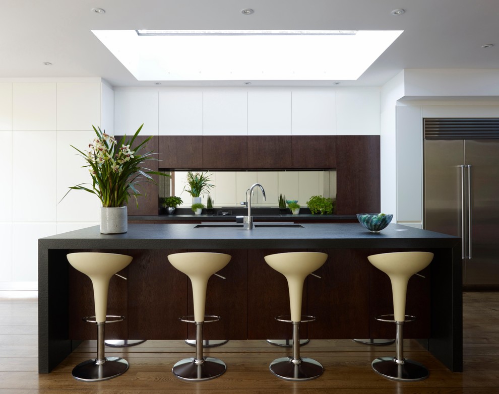 Modern inredning av ett stort linjärt kök med öppen planlösning, med en dubbel diskho, släta luckor, vita skåp, spegel som stänkskydd, rostfria vitvaror, mellanmörkt trägolv och en köksö