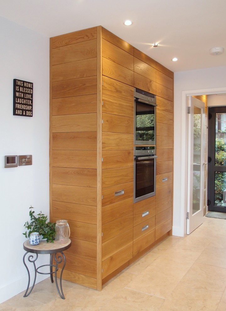 This is an example of a medium sized contemporary l-shaped kitchen in Cornwall with flat-panel cabinets, medium wood cabinets, wood worktops, stainless steel appliances, porcelain flooring and no island.