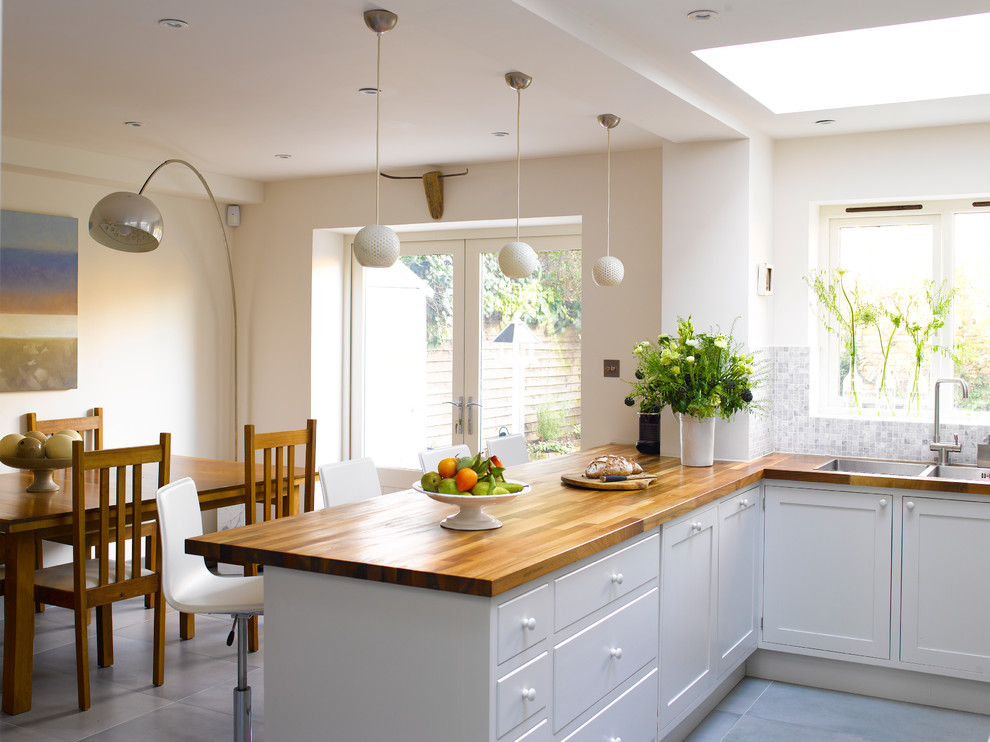 Foto de cocina actual con encimera de madera, península, salpicadero verde y electrodomésticos de acero inoxidable