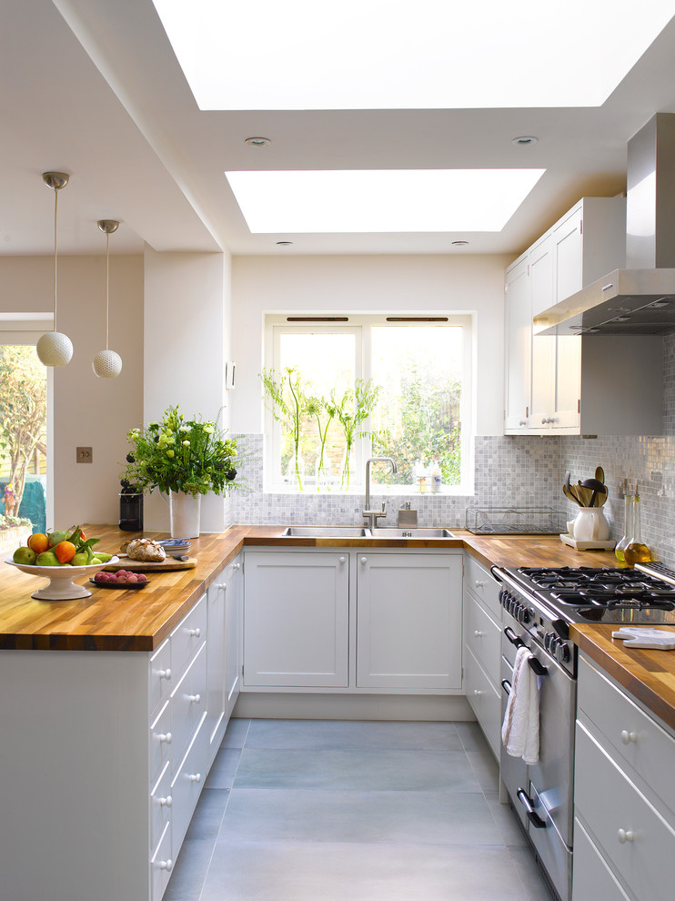 Foto di una cucina classica con ante in stile shaker, ante bianche, top in legno, paraspruzzi grigio, elettrodomestici in acciaio inossidabile e penisola