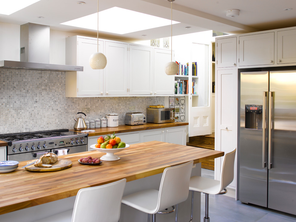 Inspiration for a traditional u-shaped kitchen/diner in London with shaker cabinets, white cabinets, wood worktops, grey splashback, stainless steel appliances and a breakfast bar.