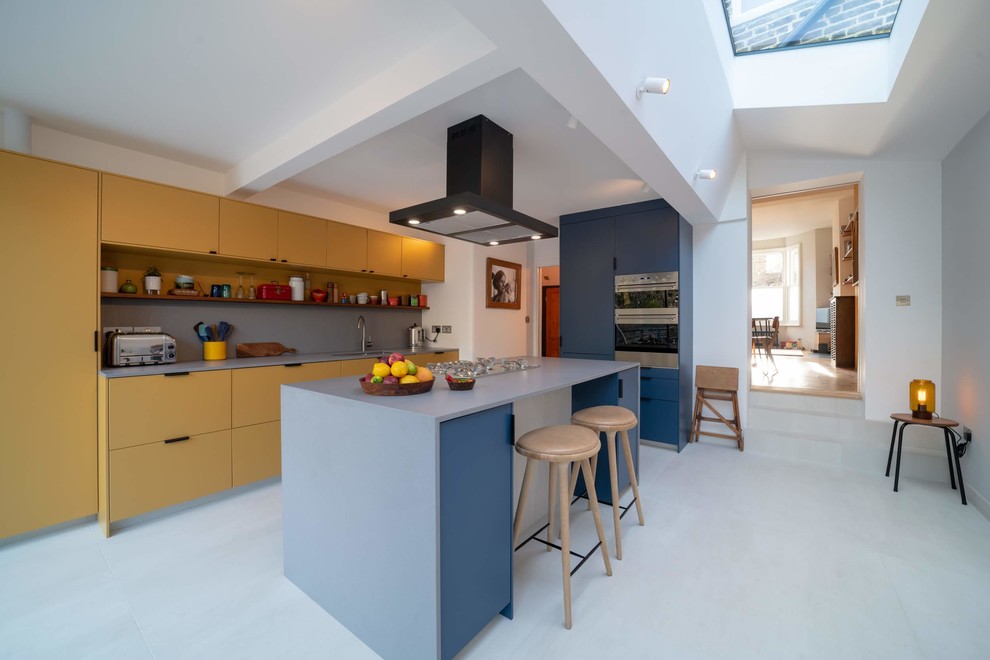 Стильный дизайн: угловая кухня-гостиная среднего размера в современном стиле с желтыми фасадами, островом и синей столешницей - последний тренд