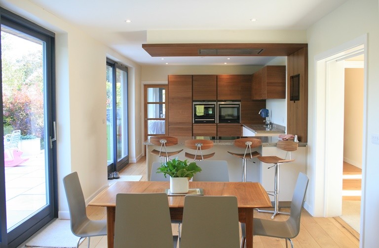 Foto di una cucina design di medie dimensioni con ante lisce, elettrodomestici neri, pavimento in legno massello medio e penisola
