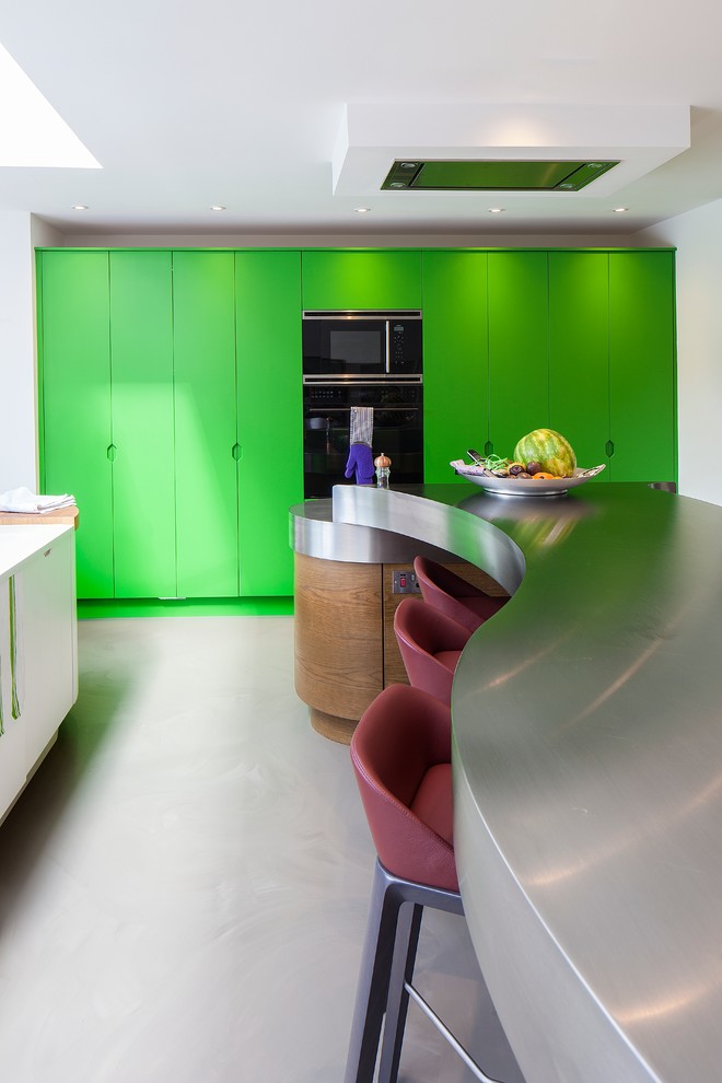 Photo of a large contemporary u-shaped kitchen/diner in Hertfordshire with a submerged sink, flat-panel cabinets, green cabinets, stainless steel worktops, black appliances, concrete flooring and multiple islands.