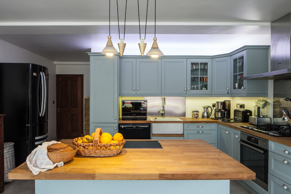 Inspiration för mellanstora klassiska l-kök, med luckor med infälld panel, en köksö, en rustik diskho, blå skåp, stänkskydd med metallisk yta och svarta vitvaror