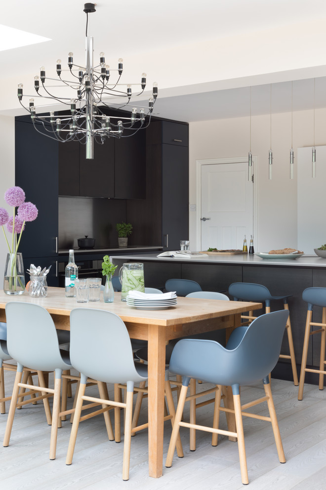 Eat-in kitchen - large contemporary medium tone wood floor and gray floor eat-in kitchen idea in Sussex with a drop-in sink, flat-panel cabinets, dark wood cabinets, solid surface countertops, metallic backsplash, stainless steel appliances, an island and gray countertops