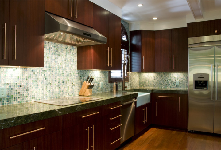 Inspiration for a tropical l-shaped eat-in kitchen remodel in Miami with a farmhouse sink, flat-panel cabinets, dark wood cabinets, granite countertops, blue backsplash, mosaic tile backsplash and stainless steel appliances