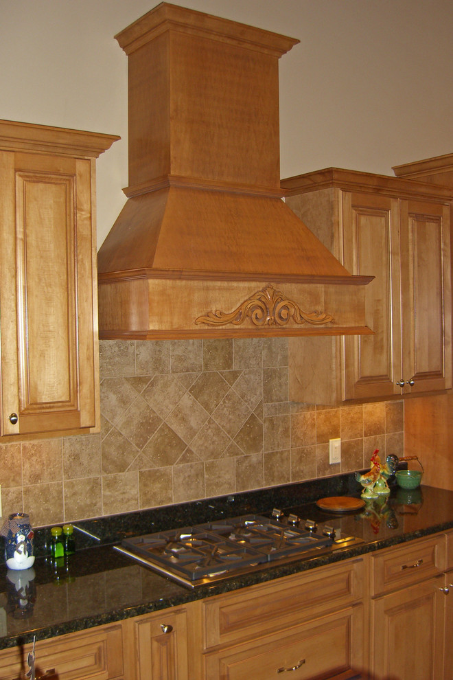 Example of a classic kitchen design in Milwaukee with raised-panel cabinets, medium tone wood cabinets, granite countertops, brown backsplash and stone tile backsplash