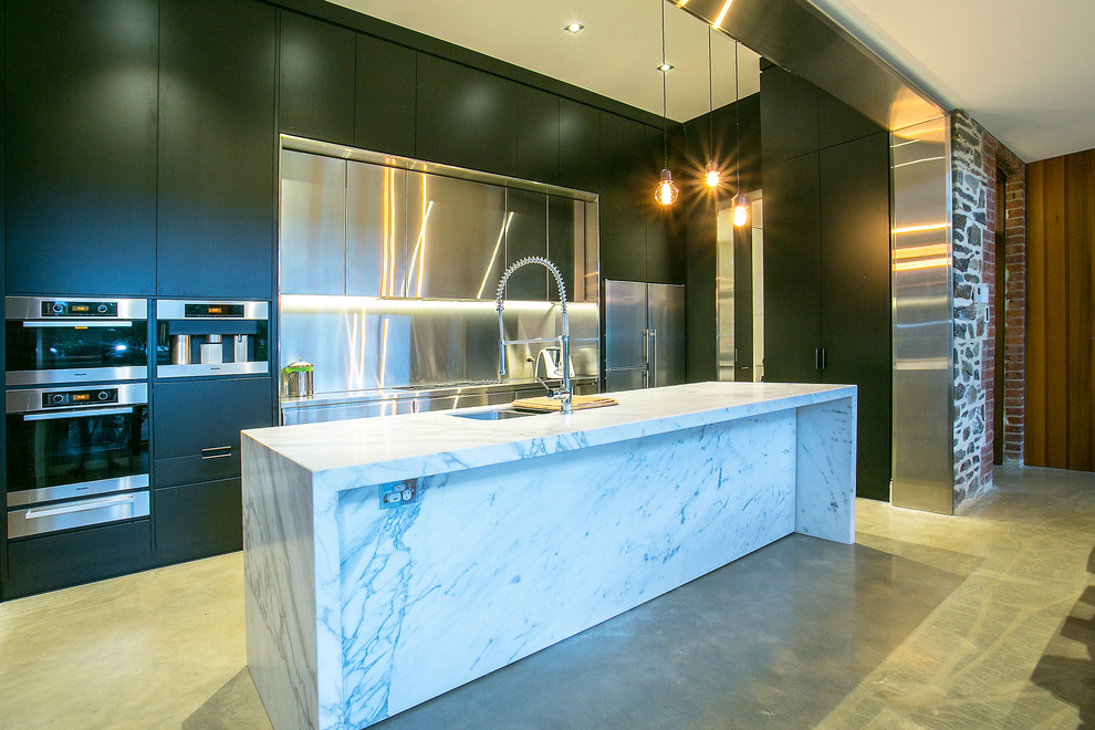 Esempio di un cucina con isola centrale moderno di medie dimensioni con lavello sottopiano, top in marmo, paraspruzzi con piastrelle di metallo, elettrodomestici in acciaio inossidabile, pavimento in cemento e ante nere