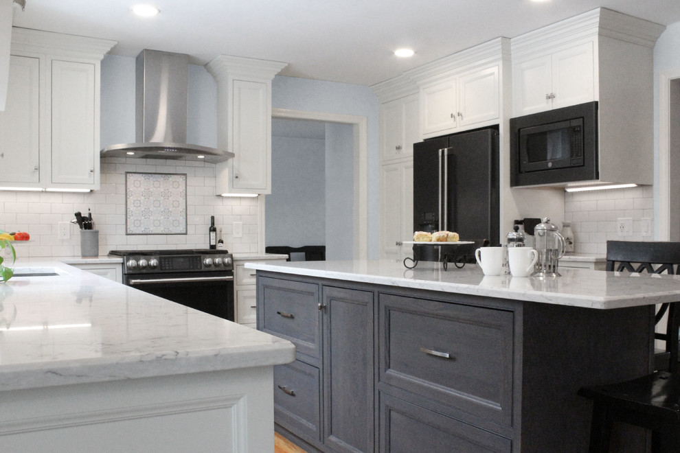 Photo of a large traditional u-shaped kitchen/diner in Boston with a submerged sink, shaker cabinets, white cabinets, engineered stone countertops, white splashback, ceramic splashback, black appliances, medium hardwood flooring, an island, brown floors and white worktops.