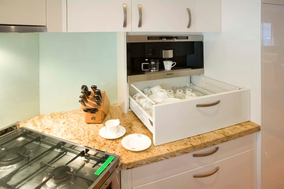 Immagine di una cucina moderna di medie dimensioni con ante lisce, ante bianche, top in granito, paraspruzzi verde, paraspruzzi con piastrelle di vetro e elettrodomestici in acciaio inossidabile