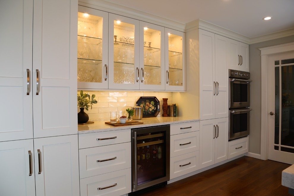 Example of a large transitional l-shaped medium tone wood floor eat-in kitchen design in Other with an undermount sink, shaker cabinets, white cabinets, quartz countertops, white backsplash, subway tile backsplash, stainless steel appliances and an island