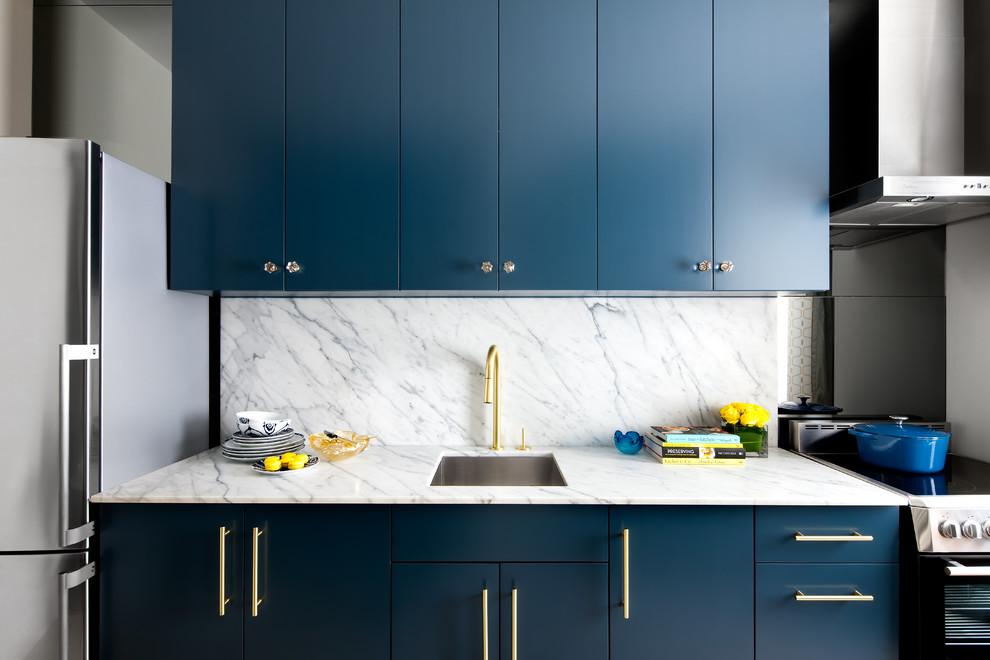 Foto di una cucina lineare design con lavello sottopiano, ante lisce, ante blu, paraspruzzi bianco, elettrodomestici in acciaio inossidabile, nessuna isola e paraspruzzi in lastra di pietra