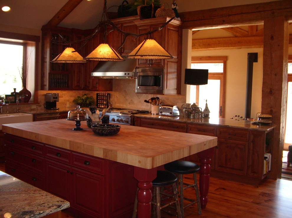 Immagine di una grande cucina stile rurale con ante con bugna sagomata, ante rosse, top in legno, paraspruzzi beige e paraspruzzi con piastrelle in pietra