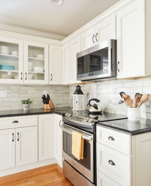 fabuwood fusion blanc door style with black quartz countertop and brick style backsplash . glass door cabinets .crown molding and butcher block countertop on island.
Eat-in kitchen - mid-sized transitional l-shaped light wood floor eat-in kitchen idea in Other with an undermount sink, recessed-panel cabinets, beige cabinets, quartz countertops, multicolored backsplash, brick backsplash, stainless steel appliances, an island and black countertops