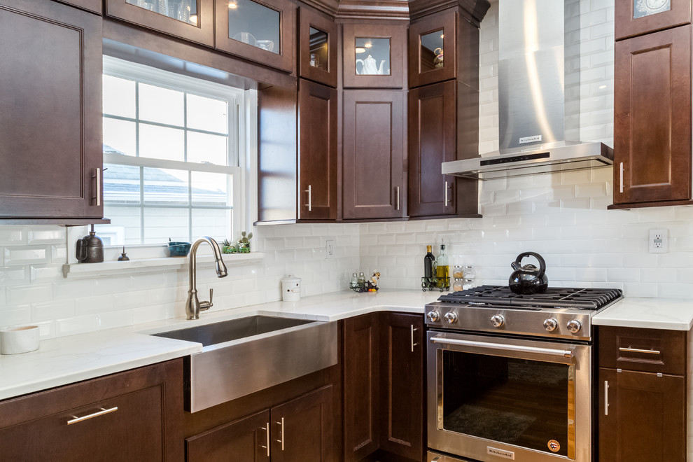 Inredning av ett modernt mellanstort kök, med en rustik diskho, skåp i shakerstil, bruna skåp, granitbänkskiva, vitt stänkskydd, stänkskydd i tunnelbanekakel, rostfria vitvaror, ljust trägolv, en halv köksö och brunt golv