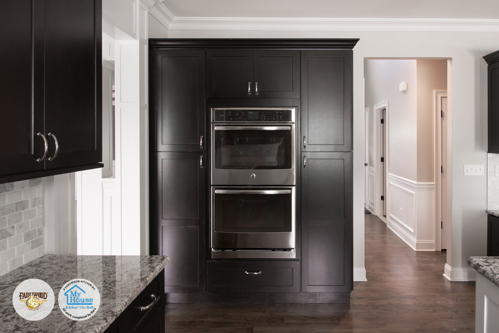 Mid-sized transitional kitchen photo in Newark with dark wood cabinets, stainless steel appliances and an island