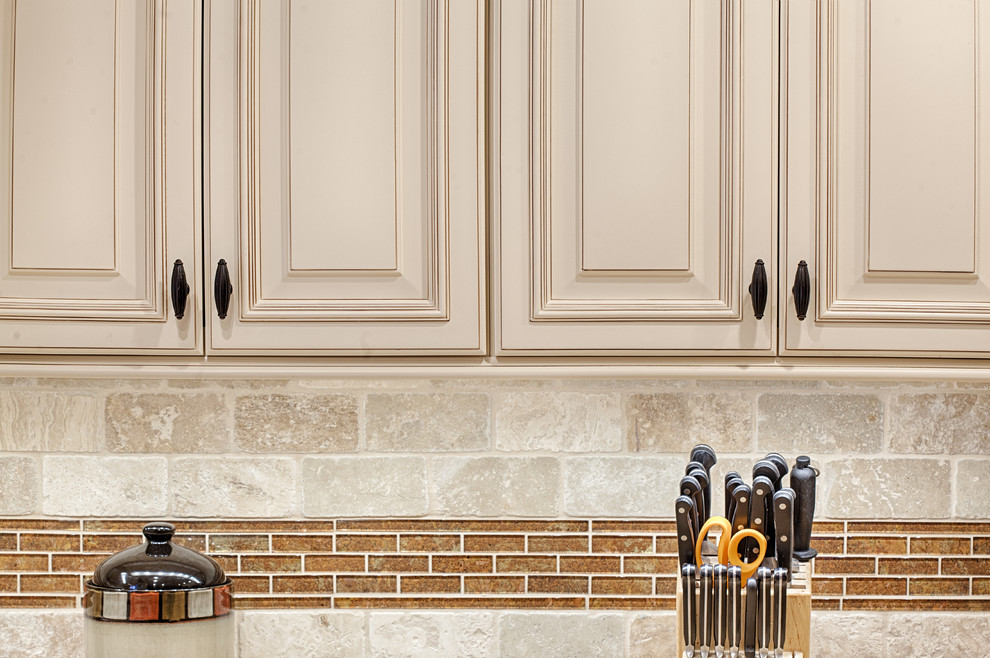 Klassisk inredning av ett stort kök, med luckor med upphöjd panel, granitbänkskiva, beige stänkskydd, rostfria vitvaror, en köksö, en undermonterad diskho, vita skåp, stänkskydd i stenkakel, klinkergolv i porslin och beiget golv