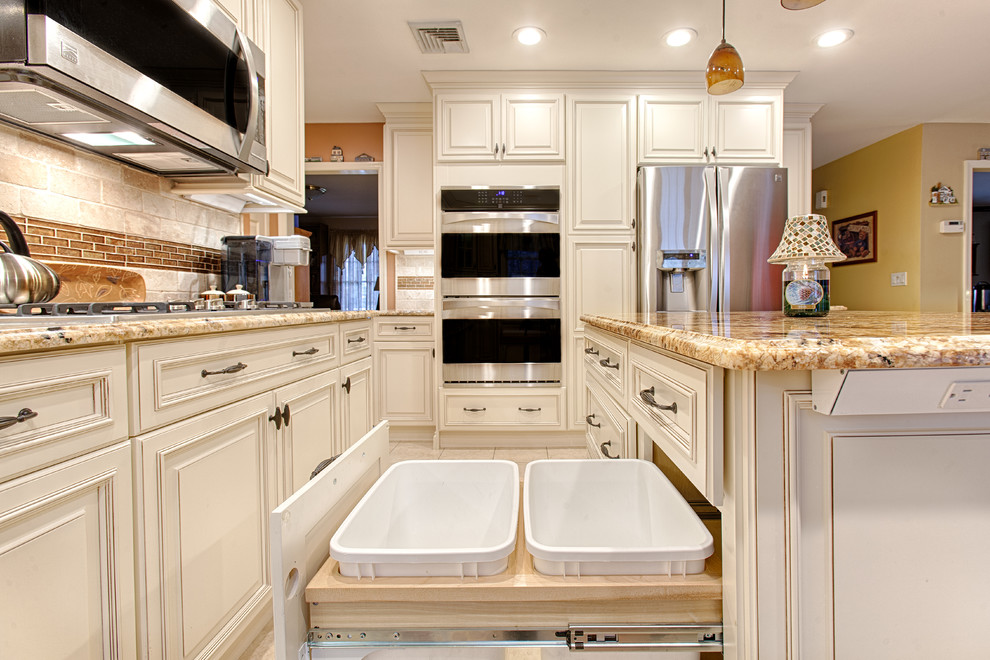 Large elegant l-shaped porcelain tile and beige floor eat-in kitchen photo in New York with raised-panel cabinets, granite countertops, beige backsplash, stainless steel appliances, an island, an undermount sink, white cabinets and stone tile backsplash