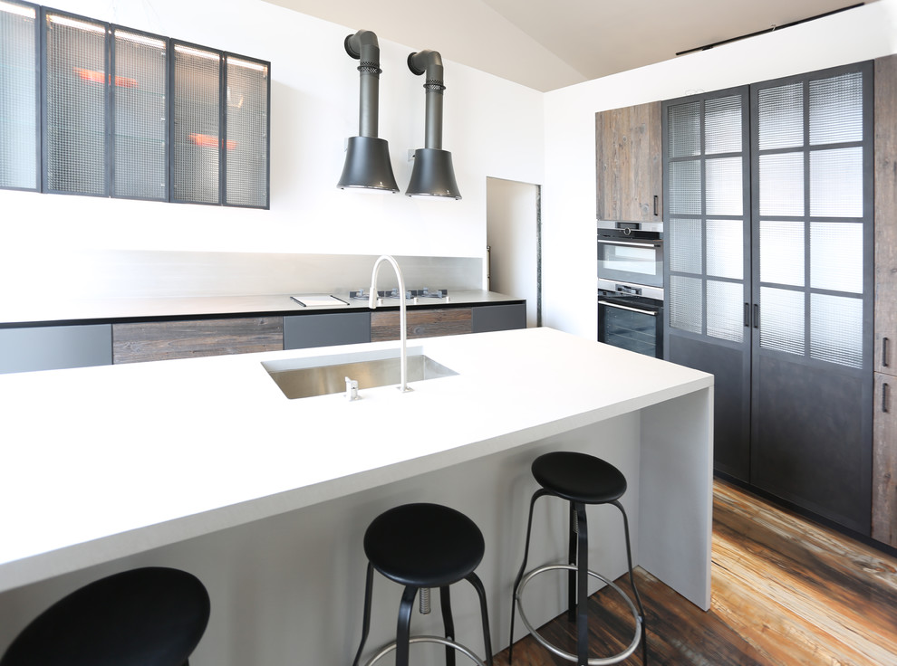 Large contemporary open plan kitchen in Other with a submerged sink, beaded cabinets, medium wood cabinets, concrete worktops, stainless steel appliances, porcelain flooring, an island, multi-coloured floors and grey worktops.