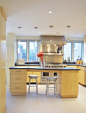 Foto de cocina contemporánea con armarios con paneles lisos, puertas de armario de madera clara, electrodomésticos de acero inoxidable, suelo de madera clara y una isla